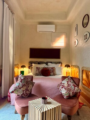 A hotel room with a bed, two bedside lamps, a large mirror, and a small side table with a decorative item. - Riad Casa Felicità (Marrakech)