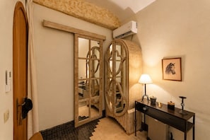 A hotel room with a wooden door, a radiator, a table with a lamp, and a framed picture on the wall. - Riad Casa Felicità (Marrakech)