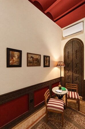 A room with a patterned floor, a round table with chairs, a wall-mounted air conditioning unit, and a decorative door. - Riad Casa Felicità (Marrakech)