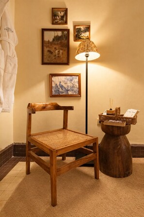 Una sedia di legno con seduta intrecciata, una lampada da terra e un tavolino in legno con un cesto e un libro.