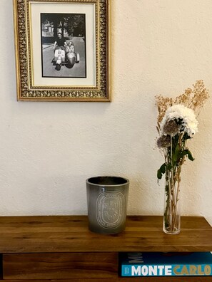 A framed black and white photo, a grey mug, and a vase with flowers on a wooden table. - Riad Casa Felicità (Marrakech)