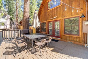 A wooden cabin with a deck, outdoor seating, and large windows. - The Canoe Cabin (Incline Village)
