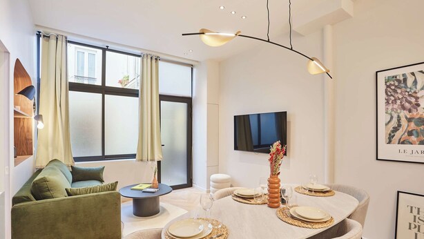 Ein modernes Wohnzimmer mit Essbereich, großen Fenstern, einem Flachbildfernseher und minimalistischer Einrichtung.