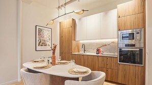 Eine moderne Küche mit Holzausbau, einer integrierten Mikrowelle und einem Essbereich mit rundem Tisch und Stühlen.