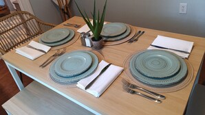 Une table à manger dressée avec des assiettes bleues, des couverts en argent et une serviette blanche.