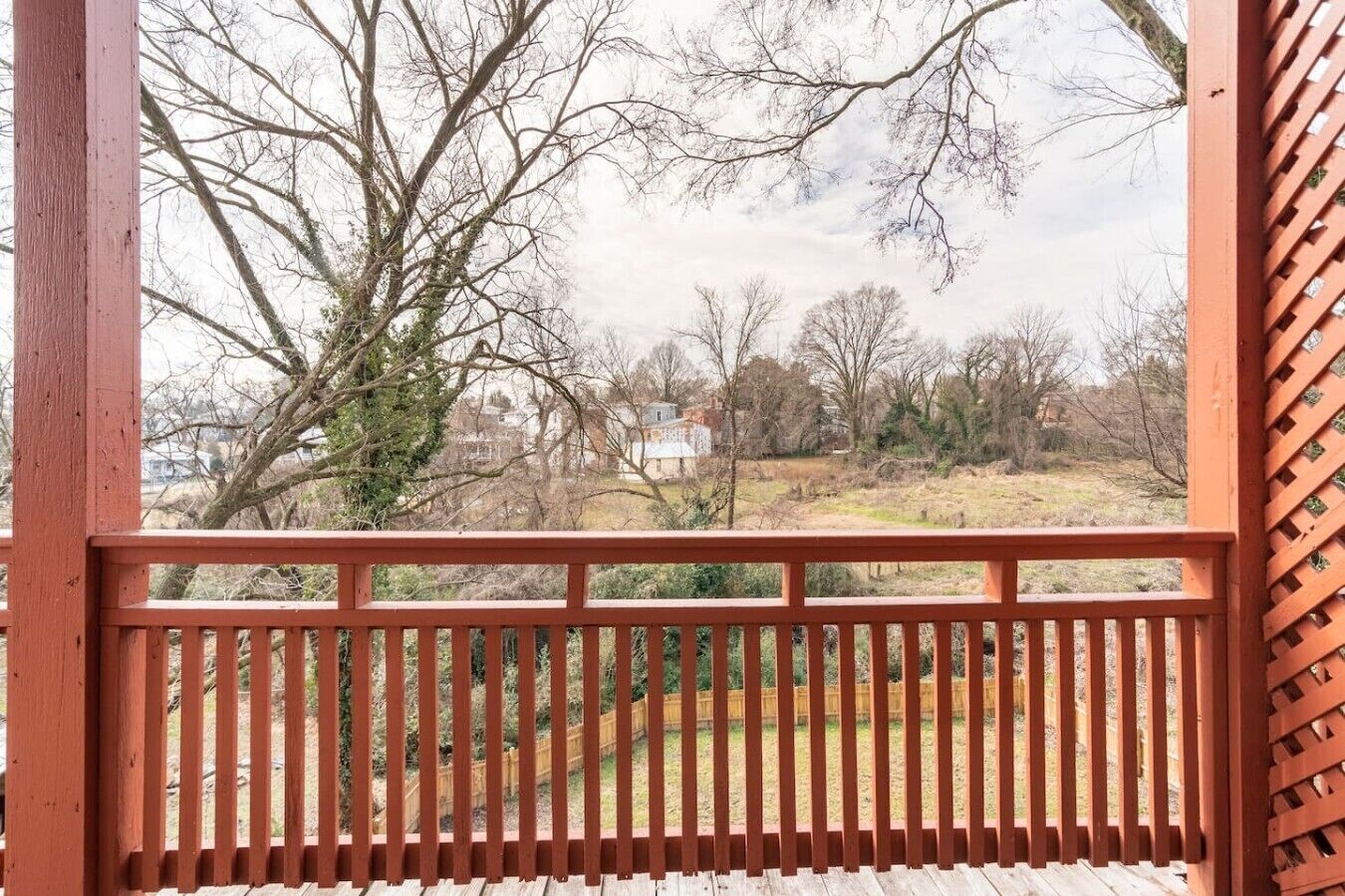 Um deck de madeira com vista para uma paisagem rural, incluindo árvores e uma casa distante.