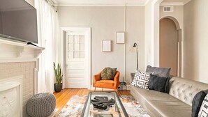 A living room with a sofa, armchair, coffee table, fireplace, and a television.