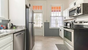 A modern kitchen with stainless steel appliances, white cabinetry, and a patterned rug.