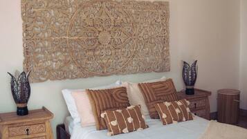 Quarto com cama grande, decoração na parede, duas mesas de cabeceira e um ventilador de teto.