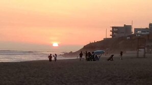 A beach with people and buildings in the background during sunset. - Hotel Brisas del Mar (Punta Negra)