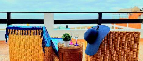 Wicker furniture on a terrace with a view of the sea.