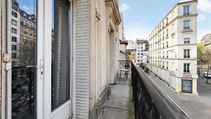 Un balcone stretto con ringhiera in metallo, affacciato su una strada con edifici.