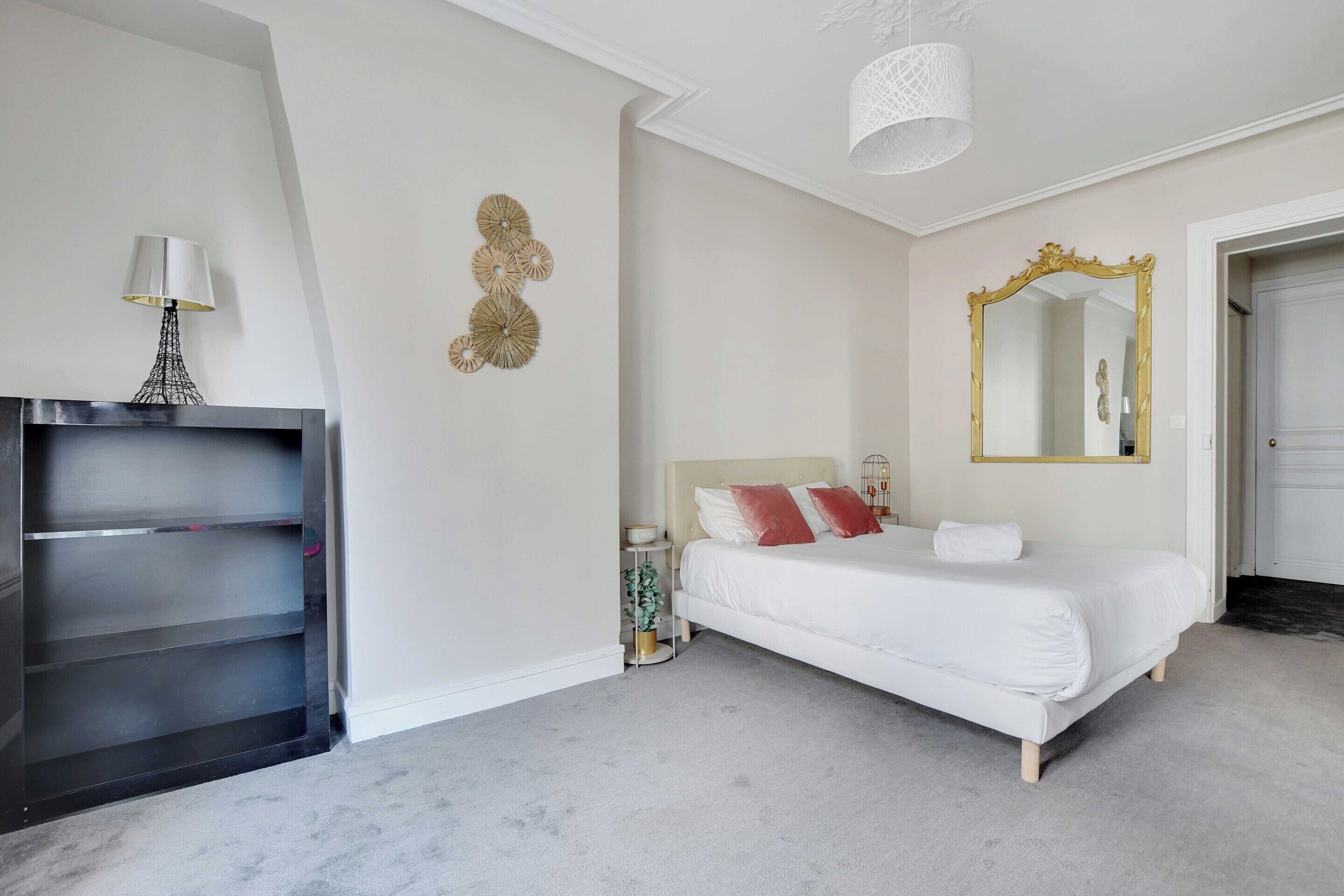 A bedroom with a bed, a dresser, a mirror, and a lamp.
