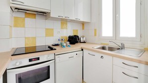 Una cucina moderna con mobili bianchi, lavastoviglie, forno, lavello e una finestra.