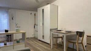 Een compacte leefruimte met een eethoek, een garderobe en een klein tafeltje met een stoel.