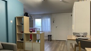 Een ruimtelijk ingerichte leefruimte met kitchenette, een eethoek en een zithoek.