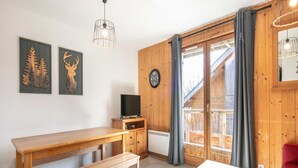 Interior de madera con una mesa, un banco y un televisor sobre un mueble de madera.