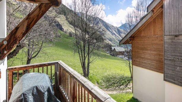 Una terraza de madera con vistas a un paisaje montañoso.