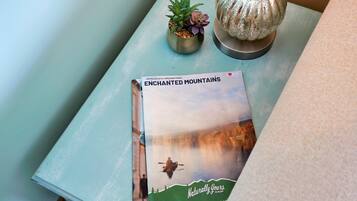 Une table sur laquelle se trouve un livre intitulé « LES MONTAGNES ENCHANTEES » et une lampe décorative.