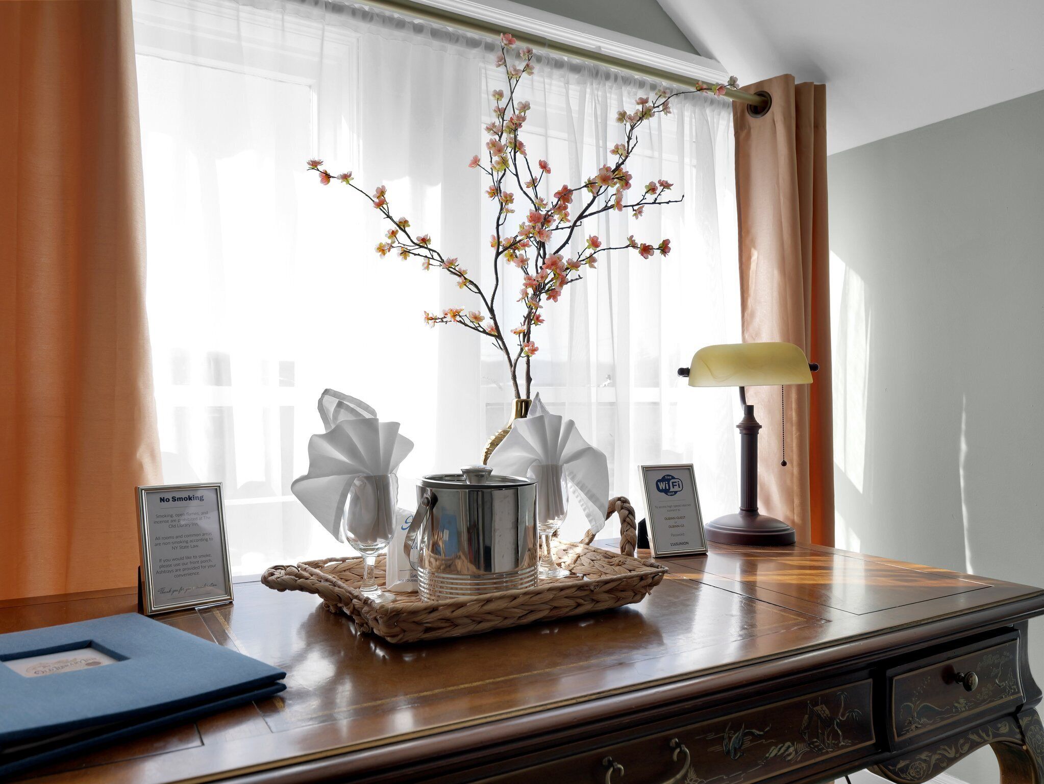 Ein Holztisch mit Blumen in einer Vase, einer Lampe und einem Schild, das kostenloses WLAN anzeigt.
