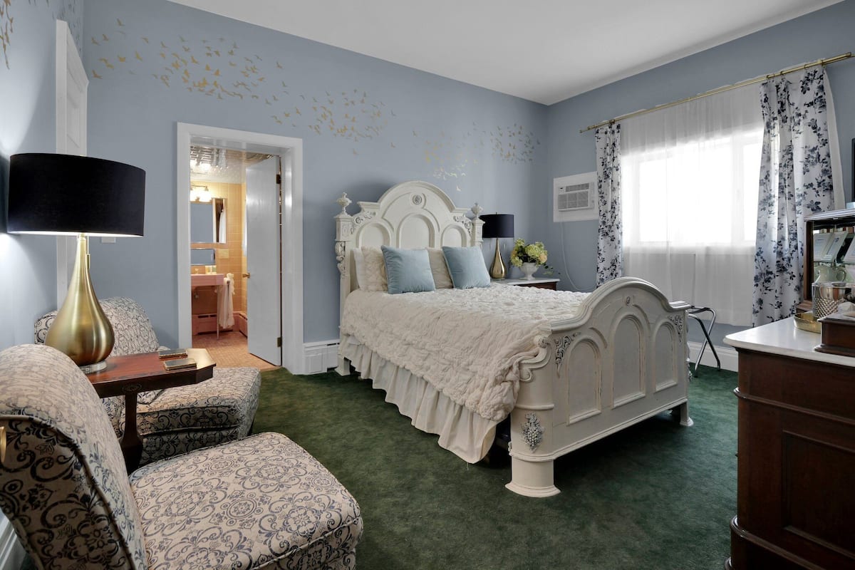 A bedroom with a large bed, a chair, a dresser, and a nightstand.