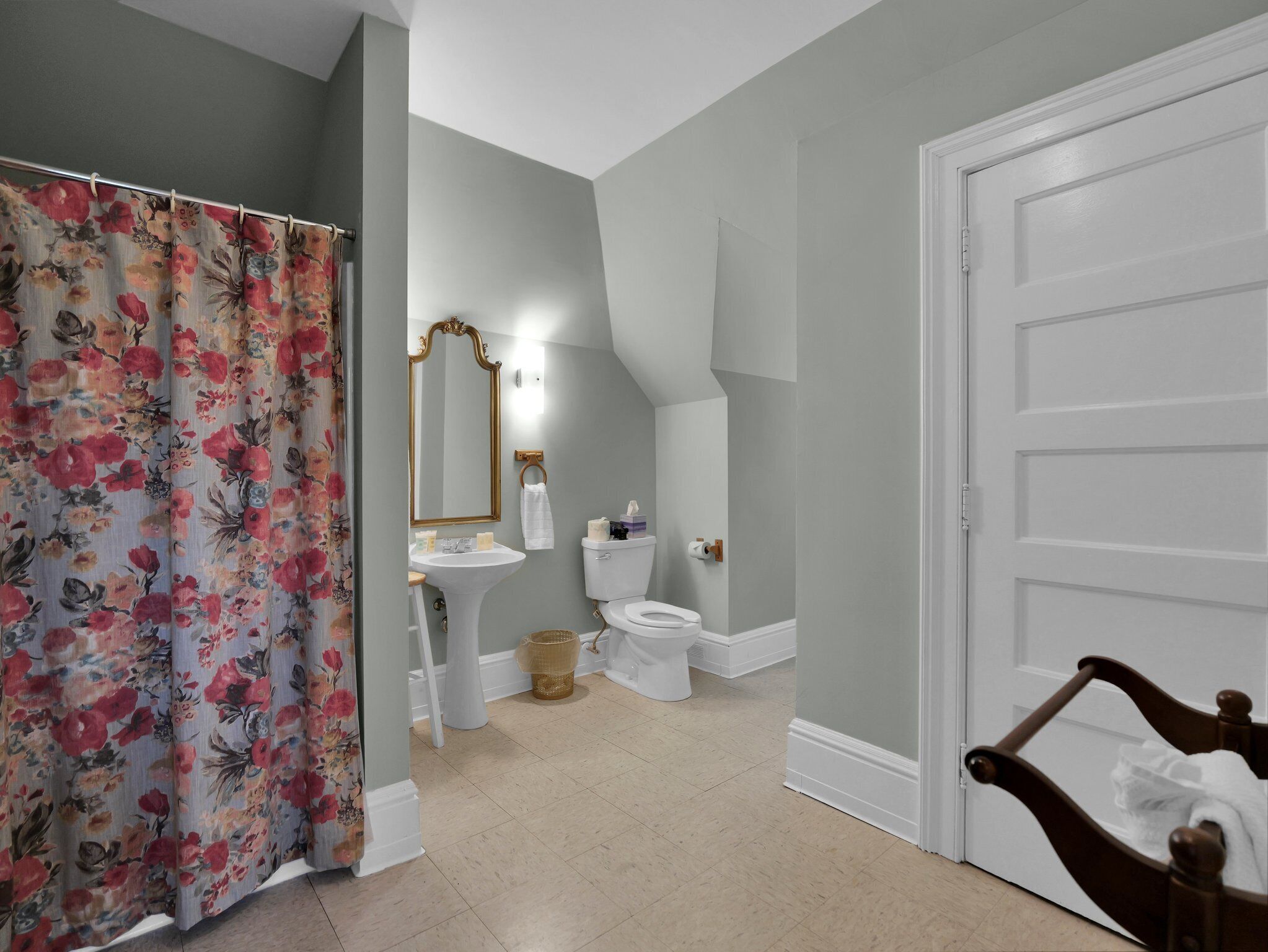 A bathroom with a shower curtain, sink, toilet, and a mirror.