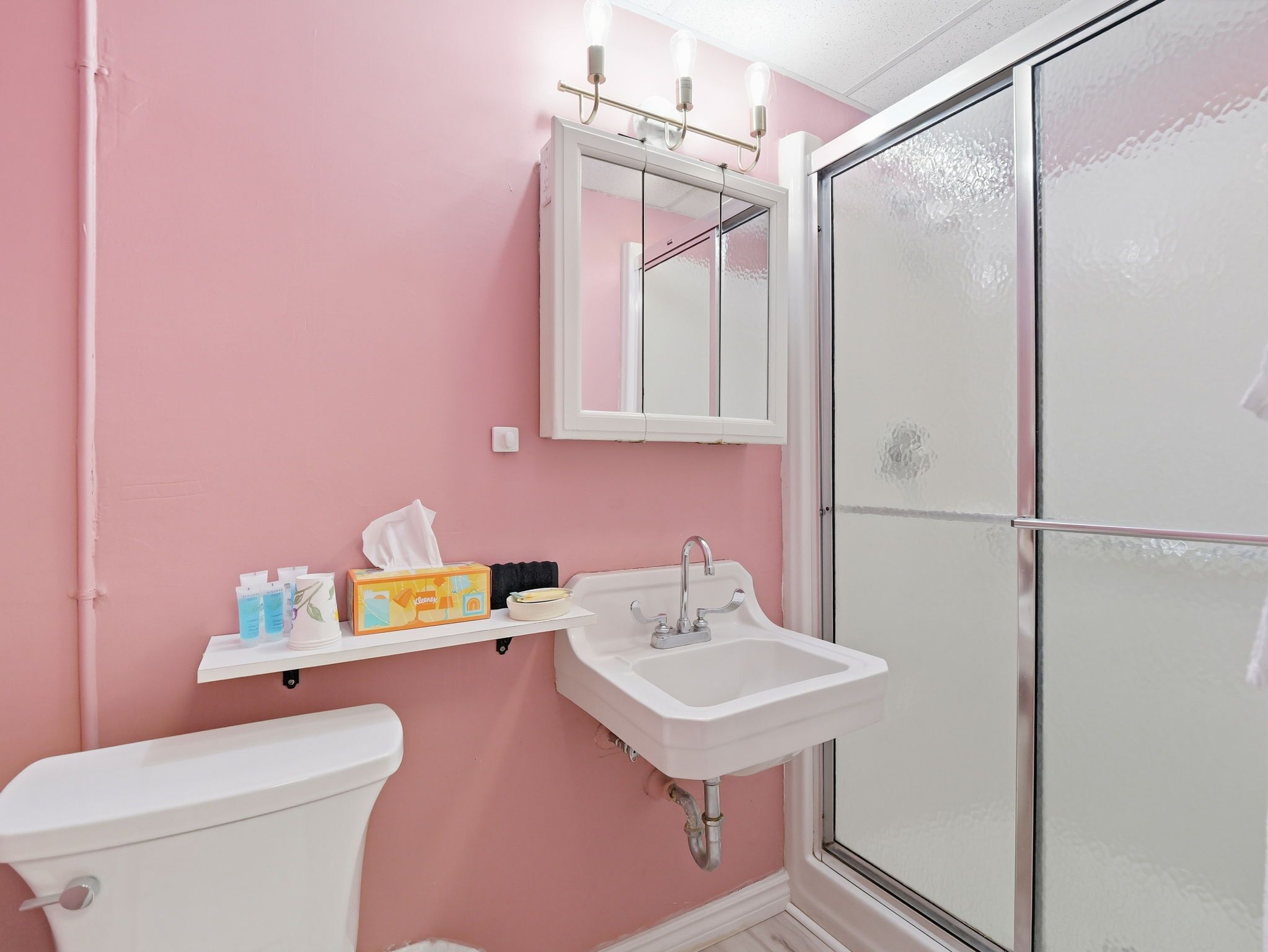Un baño con inodoro, lavamanos, espejo y cabina de ducha.