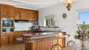 Una cocina moderna con armarios de madera, horno empotrado, microondas y una isla grande con un lavamanos.