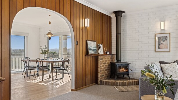 Una sala acogedora con chimenea, paredes de madera y un comedor con vistas.