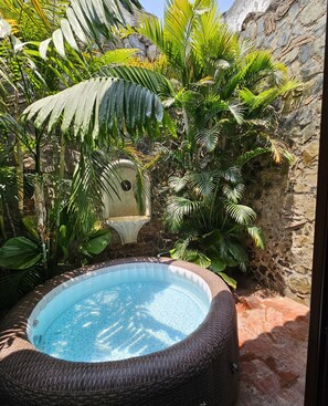 Relax in a serene garden setting surrounded by lush tropical plants and a hot tub.