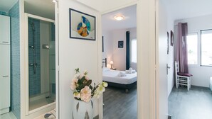 Ein Hotelzimmer mit Dusche, Bett, Nachttisch und Fenster.