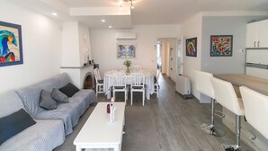 Ein modernes Wohnzimmer mit Sofa, Esstisch und Barbereich.