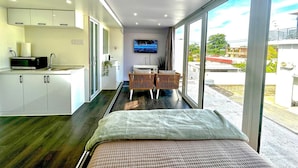 Un dormitorio moderno con una cama grande, un televisor montado en la pared y vistas al exterior a través de amplias ventanas.