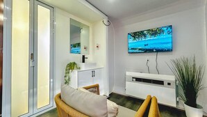 Una sala de estar moderna con un televisor montado en la pared, un sofá, un mueble y una planta en maceta.