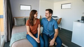Un dormitorio moderno con una cama, un escritorio pequeño y un ventanal con cortinas.