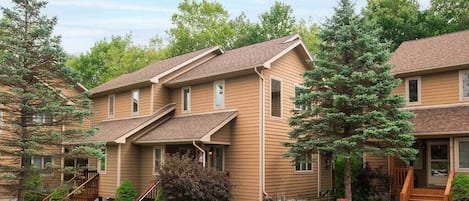 A two-story building with a covered front porch and a staircase leading to the entrance.