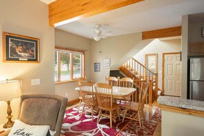A dining area with a table and chairs, a ceiling fan, and a kitchen area with a refrigerator. - 3BR Our Heart's Desire | Deep Creek Hot Tub & Fireplace (McHenry)