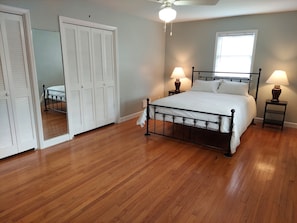 Relax in this serene bedroom with a large bed, bedside tables, and a ceiling fan.
