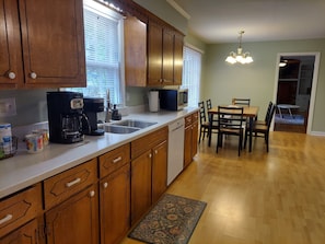 Kitchen area with dishwasher, microwave, dining table, and chandelier.