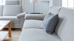 Een moderne woonkamer met een bank, een bijzettafeltje en een lamp.