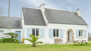 A white house with blue shutters, a stone archway, and a wooden bench. - House in Portsall Near Plage Aux Vaches (Ploudalmezeau)