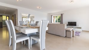 Una sala de estar moderna con comedor, sofá, televisor y mesa de comedor con sillas.