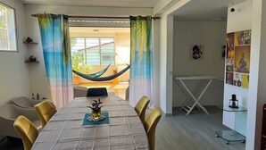 A dining area with a table set for four, a hammock, and a view of the outdoors. - Villa Aloha - Large capacity with garden, jacuzzi, + cistern_Bas du fort (Le Gosier)