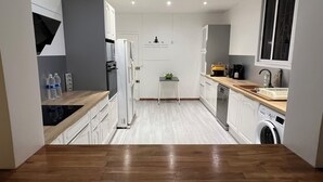 A modern kitchen with white cabinets, a wooden countertop, and built-in appliances. - Villa Aloha - Large capacity with garden, jacuzzi, + cistern_Bas du fort (Le Gosier)