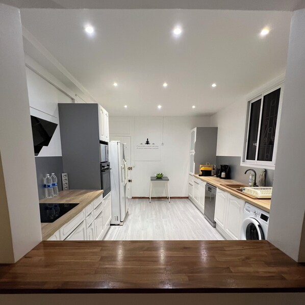 A modern kitchen with white cabinets, a wooden countertop, and built-in appliances.
