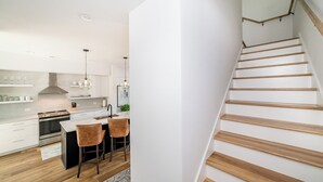 A modern kitchen with white cabinets, a central island, and wooden flooring.