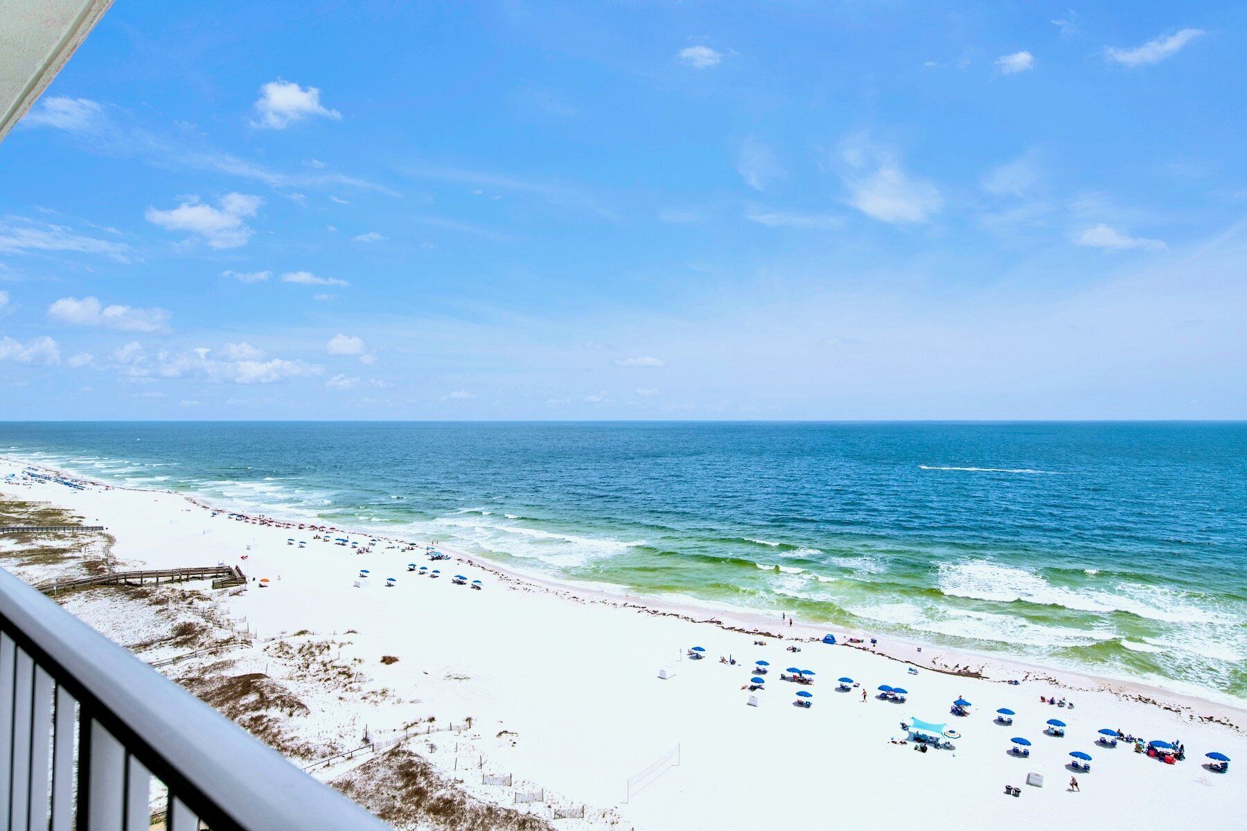 A beach with white sand, ocean waves, and a clear sky.