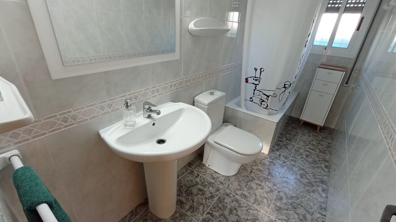 Een badkamer met een wastafel, toilet en handdoekhouder.