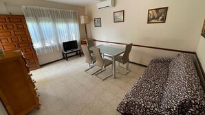 Habitación de hotel con cama, escritorio con sillas, televisión y ventana con cortinas.