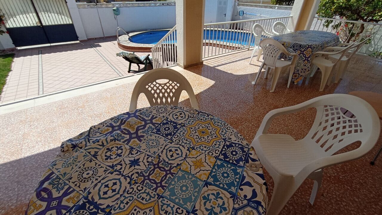 A patio area with a pool, outdoor seating, and a covered table.